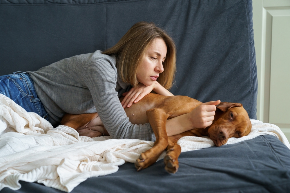 Worried woman caring for her weakening senior dog at home — knowing when to seek veterinary care